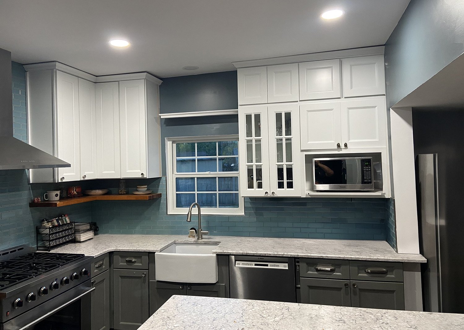 Remodeled kitchen with white cabinets and blue tile backsplash